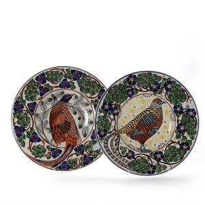To runde fade af fajance, dekorerede i farver, spejl med bl.a. fasan, blomster og bladværk. Aluminia. Diam. 46 cm. 2