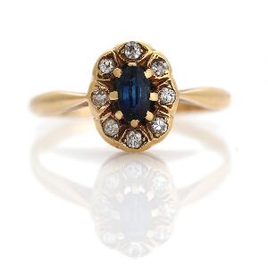 Safir- og diamantring af 14 kt. guld prydet med facetslebet safir omkranset af enkeltslebne diamanter. Str. 54.