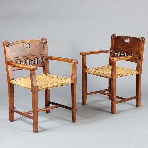 Et par almue armstole af delvis poleret træ, prydet med skæringer, sæde med flettet bast. 19. årh. 2