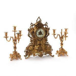 Urganiture af forgyldt bronze bestående af kaminur støbt med ornamentik samt to kandelabre. C. 1900. H. 32-49 cm. 3
