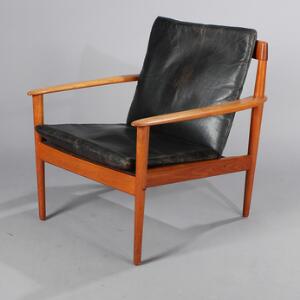 Grete Jalk Lænestol af teak, løs hynde i sæde og ryg med betræk af sort skind. Udført hos P. Jeppesen.