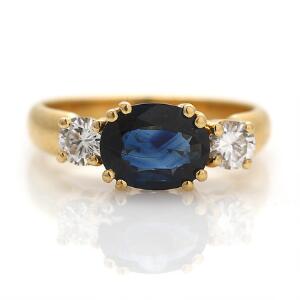 Safir-og diamantring af 18 kt. guld prydet med facetslebet safir flankeret af brillantslebne diamanter på ialt ca. 0.40 ct. Farve Wesselton. Klarhed VS. Str. 55