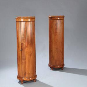 Et par runde piedestalskabe af mahogni, kannelerede med buede døre. Ca. 1900. H. 140. Diam. 41. .
