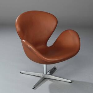 Arne Jacobsen Svanen. Armstol på firpasfod af aluminium, skalformet sæde og ryg med betræk af brunt skind.
