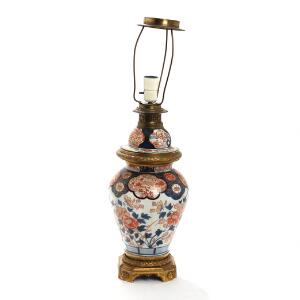 Imari bordlampe af porcelæn, monteringer af bronze, dekoreret i jernrød, blå og guld med blomster og fohunde. Meiji 1868-1912. H. 46.