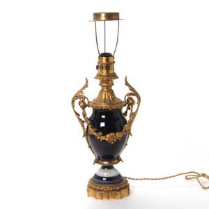 Lampe af porcelæn i form af vase, dekoreret i blå og guld, montering af forgyldt bronze støbt med bladværk. H. med montering 66 cm.