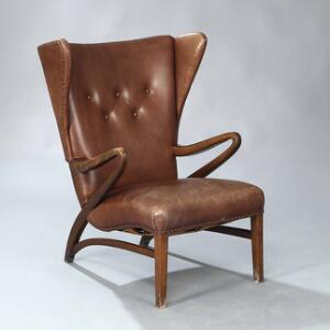Ubekendt designer Øreklapstol med stel af bejdset bøg. Sæde samt dybthæftet ryg betrukket med brun farvet patineret skind.