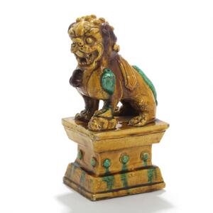Fo-hund på piedestal. Figur af keramik dekoreret med glasur i farver. 20. årh. H. 33.