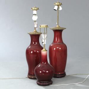 Tre kinesiske lamper af porcelæn, to baluter- og en flaskeformet med okseblodsfarvet glasur. 20. årh. H. 71. 89 og 90 cm inkl. montering. 3