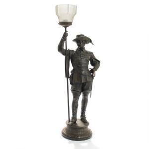 Figurlampe af metal støbt med figur i form af musketer, skærm af glas. 20. årh.s første halvdel. H. 89.