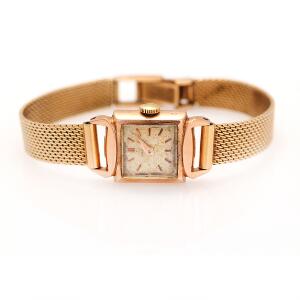 Omega Damearmbåndsur af 18 kt. guld med lys skive og gyldne visere og timemarkører. Manuelt optræk. L. 16 cm. Vægt 25 gr.