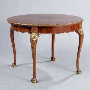 Rundt engelsk bord af mahogni, prydet med forgyldte udskæringer. Chippendale-stil. 19. årh.s slutning. H. 77. Diam. 105.