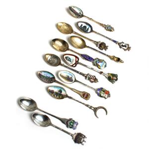 En samling på 10 souvenir-teskeer af sølv, delvis dekoreret med emalje. Samt to souvenir-teskeer af sølvplet. I æske. L. 11,3-13. 12