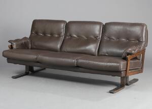 Arne Norell Tre-personers sofa med stel af mørkbejdset træ, sider, sæde, ryg og løse hynder med brunt skind. Udført hos Vatne. L. 195.