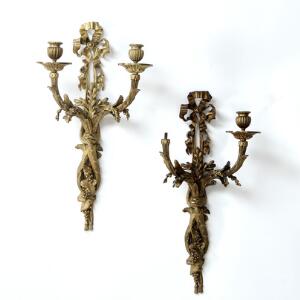Et par væglampetter af forgyldt bronze, hver med arme til to lys, prydet med sløjfe og vinløv. 19. årh. H. 57 cm.