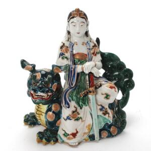 Figur af porcelæn i form af Guanyin på Shi-Shi hund, dekoreret i farver og guld. Tidlig 20. årh. H. 29 cm.