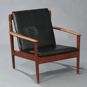 Grete Jalk Lænestol med stol af teak. Løse hynder i sæde og ryg betrukket med originalt sort skind. Udført hos P. Jeppesen.