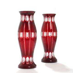Et par prydvaser af rødt Bøhmisk glas, prydet med slibninger, stående på rund fod. 20. årh. H. 32. 2