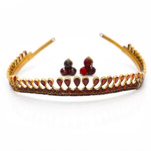 Lille Tiara af forgyldt metal prydet med talrige facetslebne granater. Et par granatøreclips af metal medfølger. Diam. ca. 12 cm. L. ca. 1,8 cm. Ca. 1890-1920.