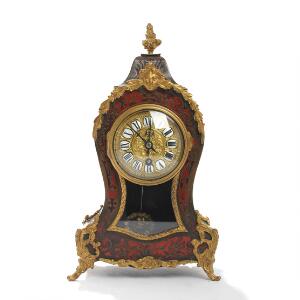 Kaminur af sortlakkeret træ, prydet med indlægninger i boulle manér, beslag af forgyldt metal. Ca. 1900. H. 33.