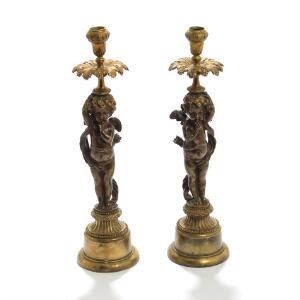 Et par lysestager af delvis forgyldt og patineret bronze, stammer i form af putti med pilekogger. Empireform. 19. årh. H. 42. 2