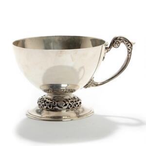 Kop af Britannia sølv, hank og gennembrudt fod smedet med blomster og bladværk, graveret med løve. 20. årh. Vægt ca. 173 gr. H. 7,5.