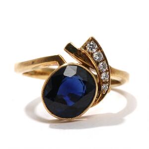 Safir- og diamantring af 14 kt. guld, prydet med oval facetsleben safir flankeret af brillantslebne diamanter på i alt 0,09 ct. Str. 52,5. 2009.