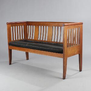 Sofabænk af mahogni med tremmer i sider og ryg, sæde monteret med sort hestehår. Empire-form, ca. 1920. H. 87. B. 142. D. 54.
