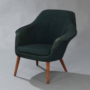 Dansk møbeldesign Lænestol med tilspidsende ben af teak. Sæde, sider samt ryg betrukket med blåsort nistret uld.