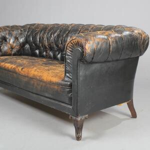 Chesterfield sofa monteret med dybhæftet sortfarvet skind på let svungne ben af mørk bejdset træ. Ca. 1900. H. 85. B. 185. D. 85.