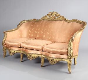 Fritstående sofa af forgyldt træ, sæder og ryg betrukket med rosafarvet stof. Rococoform, 20. årh. H. 110. B. 192. D. 100.