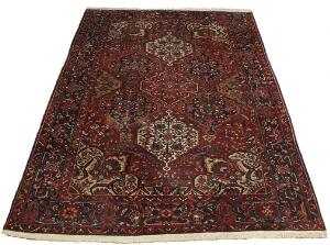 Bakhtiar tæppe, prydet med sammenhængende medaljoner, ornamentik, blomster og bladværk på rød bund. Persien. Ca. 1960. 444 x 323.