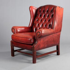 Engelsk øreklapstol med stel af mahognipoleret træ, sæde og ryg med vinrødt læder. George III form. 20. årh.s begyndelse.