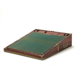 Engelsk rejseskriveskrin af mahogny, med kantlister og bæregreb af messing. 19. årh.s første halvdel. H. 18 cm. L. 51 cm. D. 28 cm.