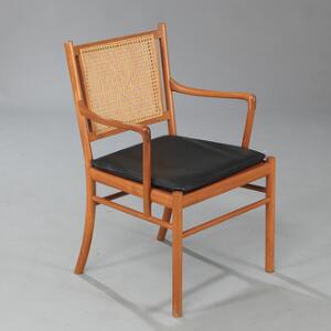 Ole Wanscher Colonial chair. Armstol med stel af mahogni. Ryg udspændt med flet. Løs sædehynde betrukket med sort skind. Udført hos P. Jeppesen.