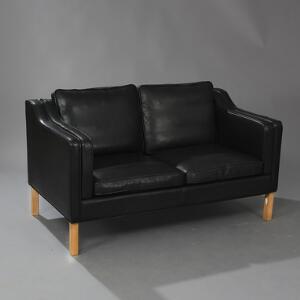 Dansk Møbelproducent Manhattan. To-personers sofa med betræk af sort skind, ben af eg. Udført hos Hurup Møbelfabrik.