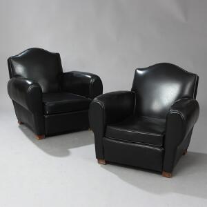 Et par clubstole med ben af bejdset bøg. Sæde, sider samt ryg betrukket med sømbeslået sort vinyl. 2