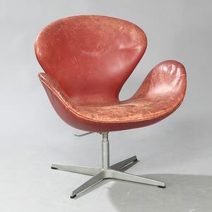 Arne Jacobsen Svanen, hvilestol på firpasfod med stamme af aluminium, skalformet sæde og ryg med betræk af rødbrunt skind.