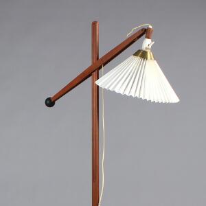 Vilhelm Wohlert Standerlampe af oregon pine med justérbar arm, monteret på fod af sortlakeret metal, med plisseret skærm. Udført hos Le Klint.
