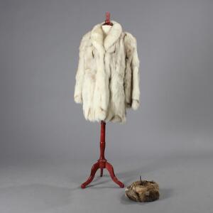 Kort frakke af polarræv samt hat af vaskebjørn. Str. ca. 42-44. L. 83. Udvendig ærmelængde ca. 65. 2