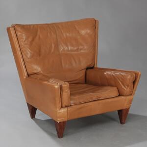 Illum Wikkelsø Lænestol med tilspidsende ben af palisander. Sider, ryg samt løse hynder betrukket med lysebrunt farvet skind. Model V11.