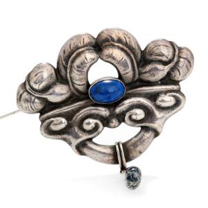 Lapis lazuli- og agatbroche af sølv prydet med cabochonslebet lapis lazuli og agat. L. ca. 7,8 cm. Ca. 1910-20.