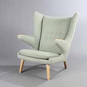 Hans J. Wegner Bamsestol. Øreklapstol med ben og negle af eg, betrukket med grønligt uld. Udført hos AP-Stolen.