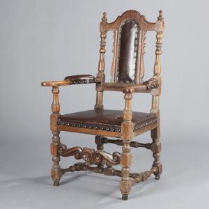Barok armstol af egetræ, prydet med skæringer, sæde, ryg og armlæn betrukket med mørkebrunt læder. 18. årh.