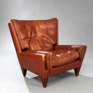 Illum Wikkelsø Lænestol med tilspidsende ben af palisander. Sider, ryg samt løse hynder betrukket med brunt farvet skind. Model V11.