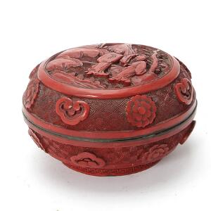 Kinesisk cinnabar æske, rigt udskåret med figurer i landskab og ornamentik. Qing, 19. årh. H. 7 cm. Diam. 11,7 cm.