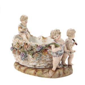 Stor jardinière af porcelæn dekoreret i farver og modeleret med pousserede blomster og børn, utydl. mærket. 19. årh. L. 35 cm.