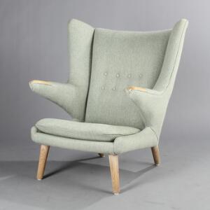 Hans J. Wegner Bamsestol. Øreklapstol med ben og negle af eg, betrukket med grønligt uld. Udført hos AP-Stolen.