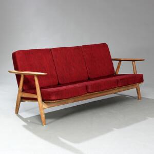 Hans J. Wegner Tre-pers. sofa med stel af massiv eg. Løse hynder i sæde og ryg betrukket med sortrødnistret uld. L. 175.