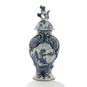 Delft vase af fajance dekoreret i underglasur blå med landskab og blomster, lågknop i form af hund. 18. årh. H. 34.
